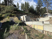 Workers in between a large wall of dirt and concrete blocks.