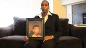 Mother of young shooting victim and violence prevention advocate seated holding a picture of her son