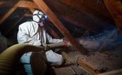 Picture of worker spraying insulation in a home attic to improve energy efficiency