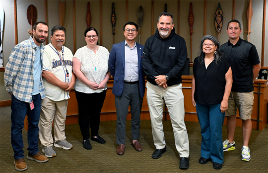 Seven people stand in front of a dais.