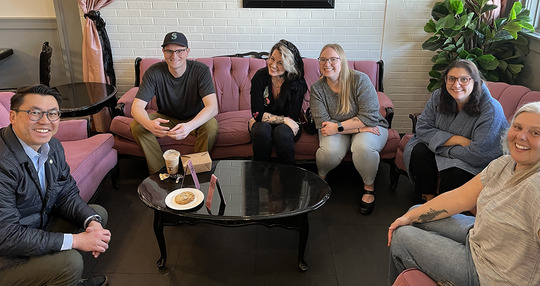 Six people sit together in a cafe.