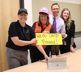 Three people in an office smiling with a sign reading "We're CHIP bound!"