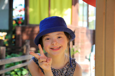 Child smiling and making a peace sign outdoors