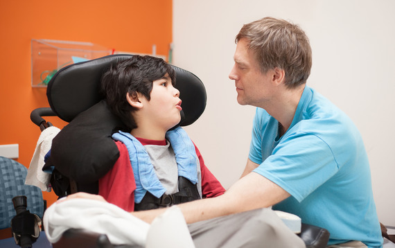 Photo of a man talking to a boy in a wheelchair.