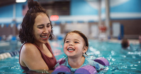 Child and adult in pool practicing water safety and swimming