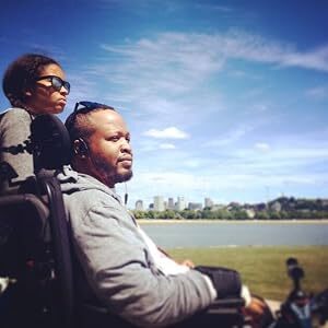 Remon Jourdan is seated in a wheelchair with a companion.