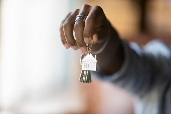 Outstretched hand holding a set of keys with a silver house charm on the keyring