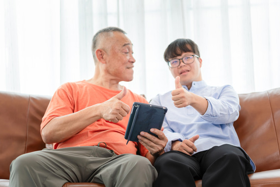 Father and son sitting on couch with iPad giving a thumbs up