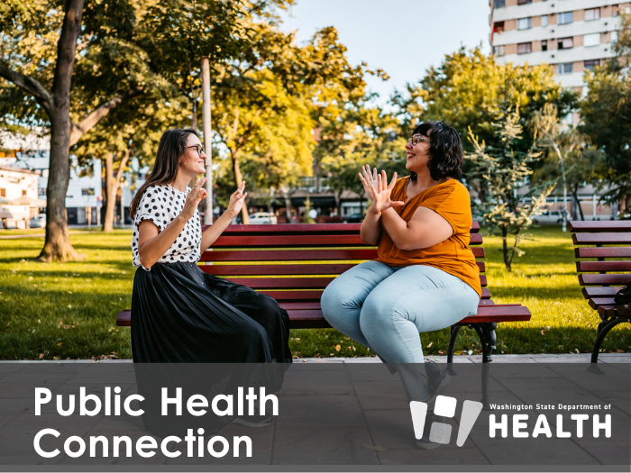 Two women sitting on a park bench facing each and using American Sign Language.