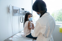 Female healthcare provider giving vaccination to a girl in a doctor's office. 