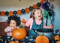 Two little girls carving pumpkins.