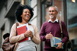 Happy mid adult African American students and her mature friend having fun while going to a library to study.