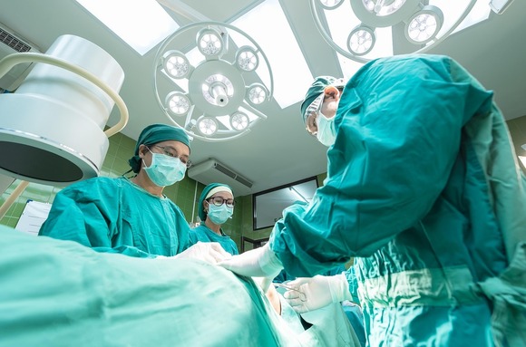 Three healthcare professionals performing surgery
