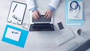 Laptop on desk with papers and medical supplies