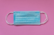 paper face masks laying on a pink background