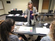 A woman in a room with desks training professionals
