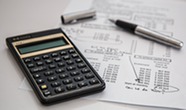 Invoice sheet, calculator, and pen on a white surface