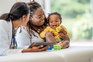 Happy toddler held by mom working with health care provider