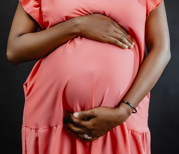 African American pregnant belly showing through coral colored dress
