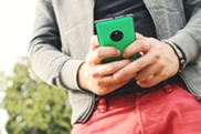 A person wearing casual clothes outdoor holding a smartphone.