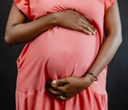 Image of a pregnant woman wearing a bright coral dress.