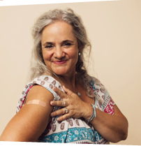Older adult woman with long gray hair showing off her band aid from being vaccinated