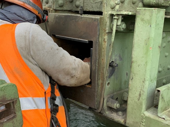 A crew member works on mechanical pieces of the Montlake Bridge.
