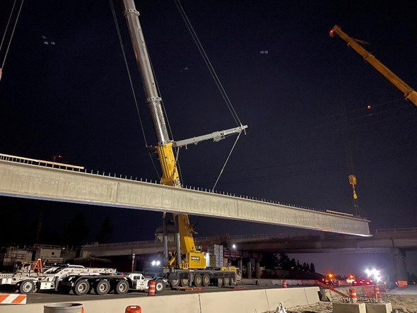 Two cranes lift the first girder into place for the new South 216th Street bridge.