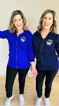 Photo of twins wearing matching blue sweatshirts and black pants posing for tik tok video