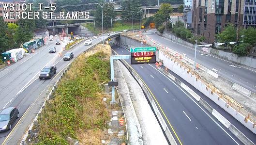 Photo shows Mercer St ramp and signage above I-5 with cars in background