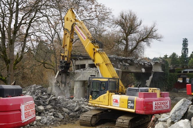 Photo shows demolition equipment operating with debris on the ground
