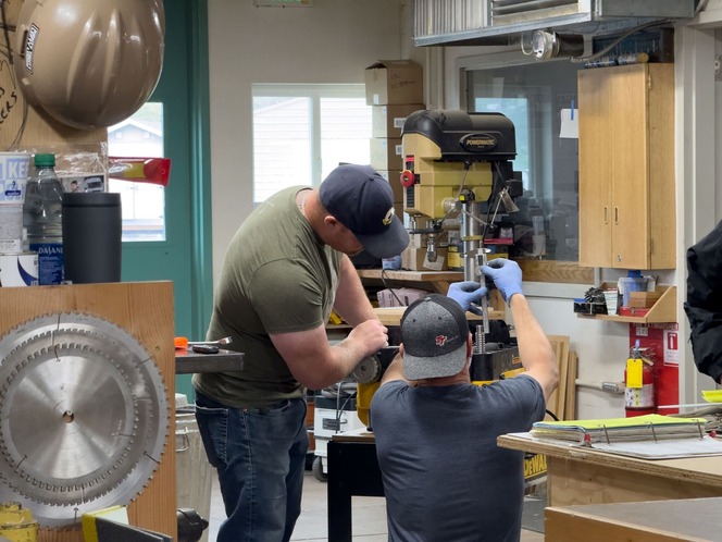 Two men working in a workshop on a drill press