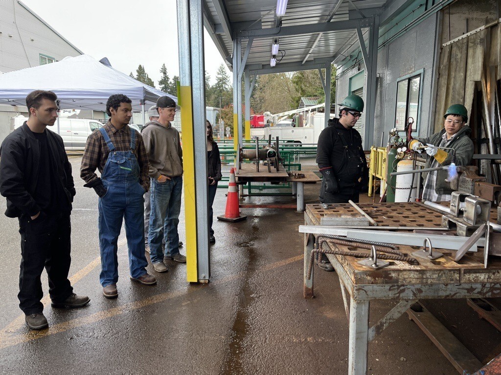 Students observing a welding demonstration outdoors