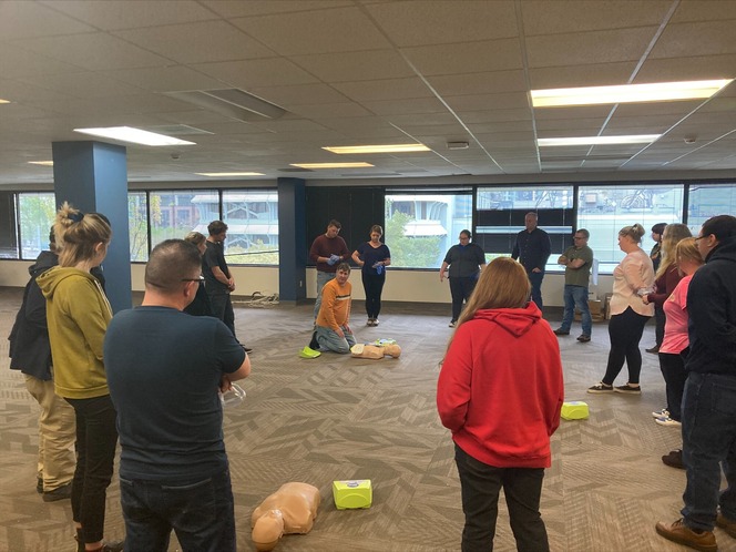 People attending a CPR training session with an instructor demonstrating on a mannequin