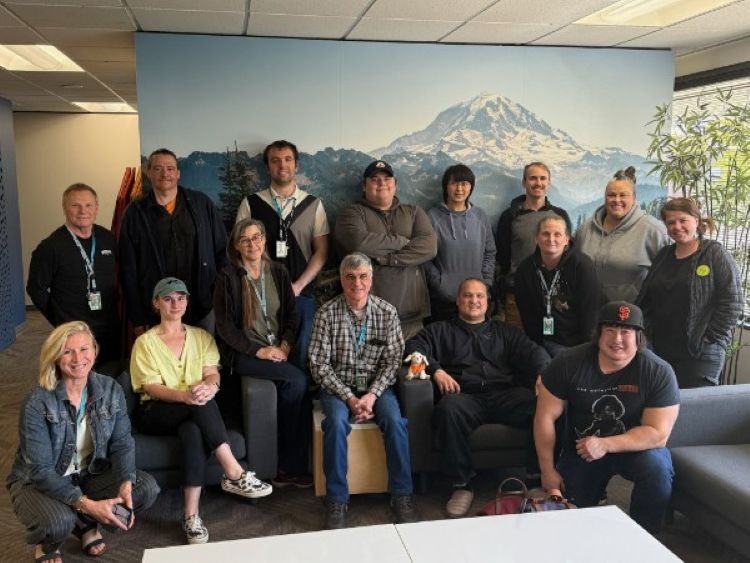 Group of people posing in front of a mountain mural in an office setting