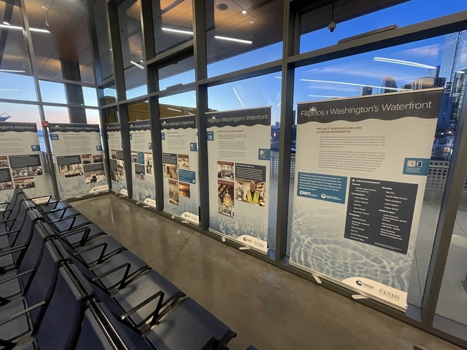 Exhibition panels about Washington's waterfront displayed in a room with large windows and black chairs