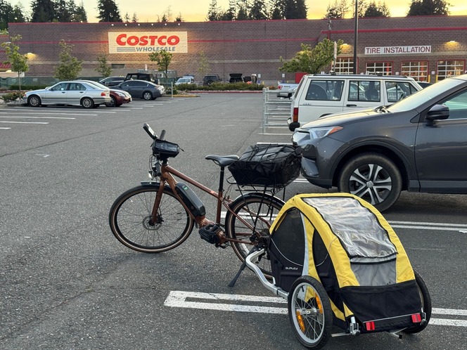 electric bicycle with trailer in front of a Costco warehouse at dusk