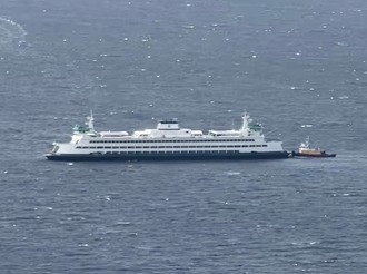 Large ferry on blue water accompanied by a tugboat.