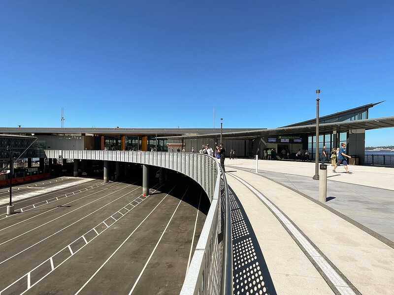 Modern transportation terminal with a curved walkway and large glass-paneled building.