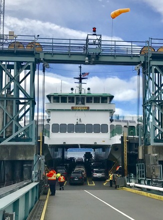 Ferry "Issaquah" docked with cars boarded and crew in orange vests on the ramp.