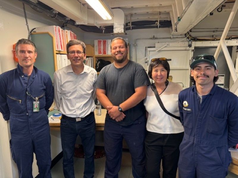 Group of five people standing indoors in a room with industrial decor.