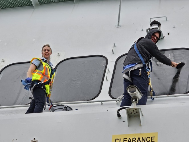 Two workers cleaning windows on ferry.