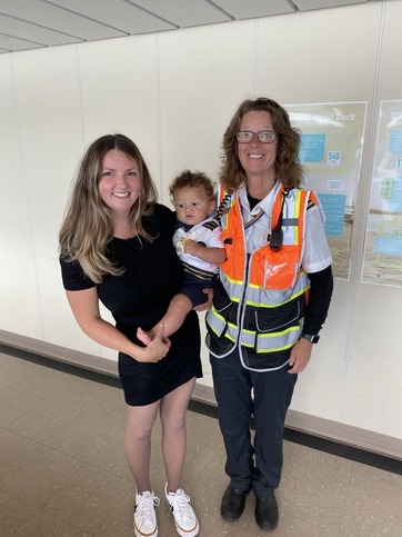 Two adults and a child standing indoors, one adult in a black dress and another in ferry crew member clothing.