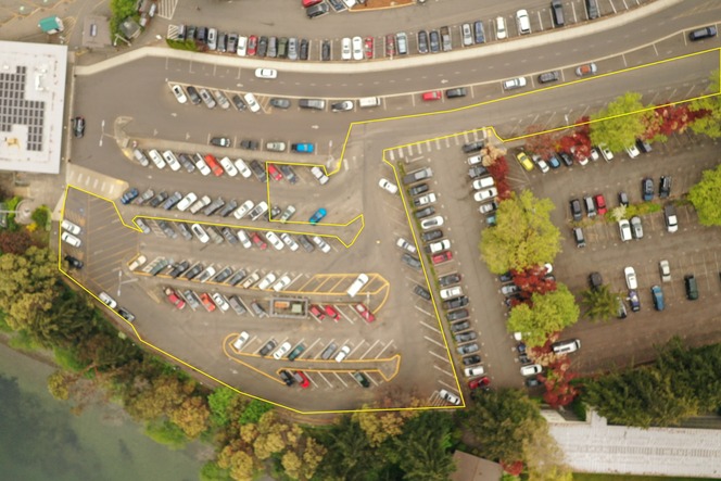 Aerial view of a parking lot with some parked cars. A large section of the lot is outlined in yellow.