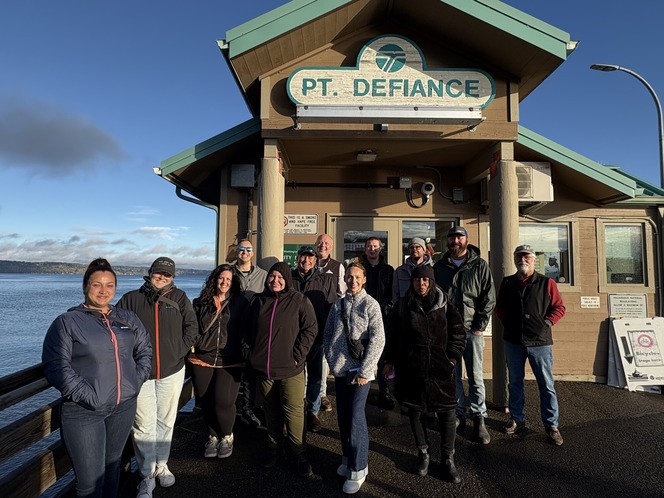 A group of people standing outside a building with a "PT. DEFIANCE" sign.