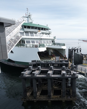 A large ferry docked at a terminal with docking infrastructure in the foreground.
