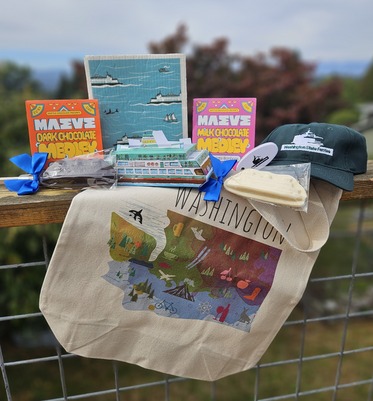 Assorted Washington state-themed products including a tote bag, chocolates, a model ferry, tea towel, cap and chocolate shaped like a ferry.