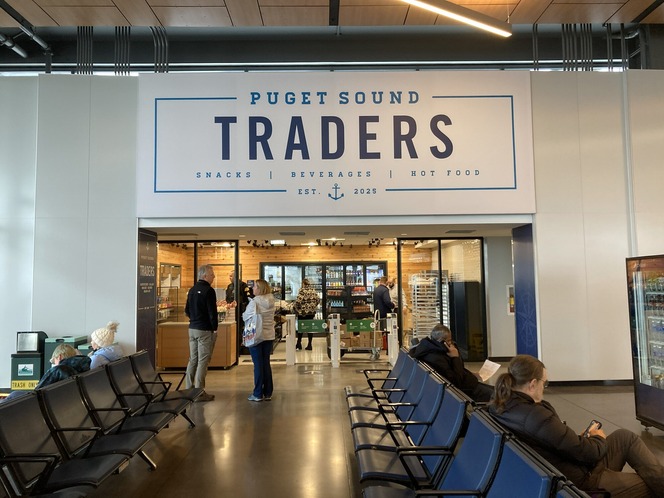 Entrance to Puget Sound Traders shop with people in a waiting area.
