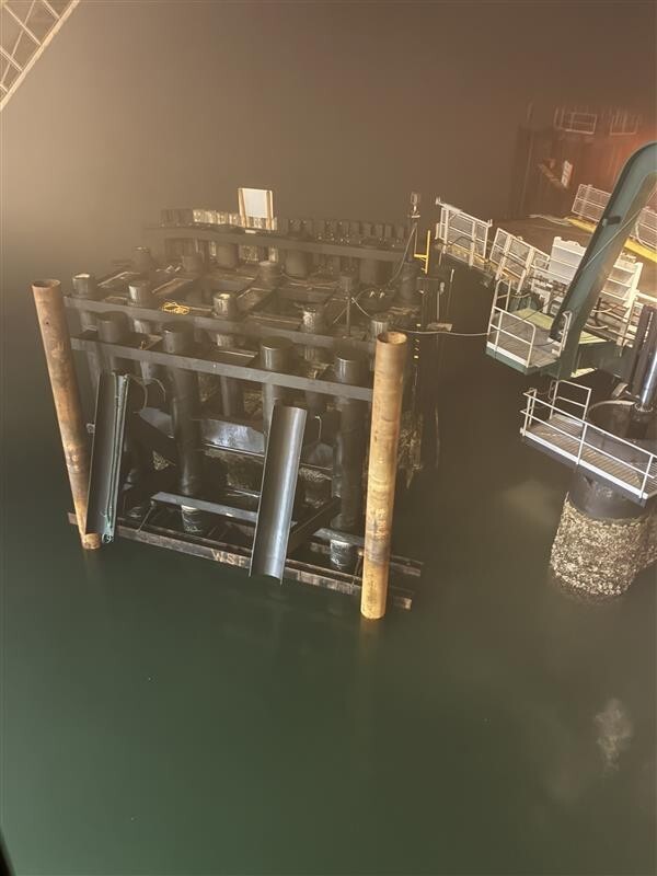 Large industrial structure partially submerged in water with metal beams and cylindrical columns at Mukilteo terminal.