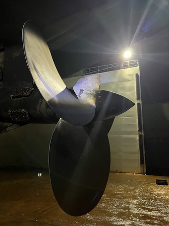 Large propeller as seen out of water with ferry in dry dock.